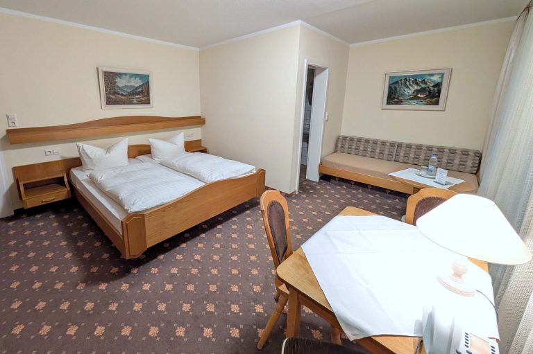 Helles Hotelzimmer mit zwei Betten, einer Couch und Tisch.