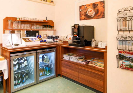 Küchenzeile mit Kühlschrank, Kaffeemaschine und Ablagen für Getränke.