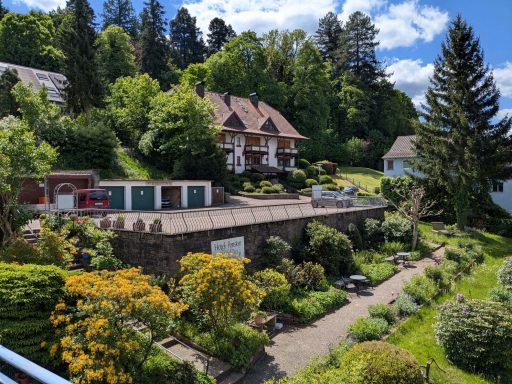 Idyllische Gartenlandschaft mit mehreren Häusern und üppigem Grün.