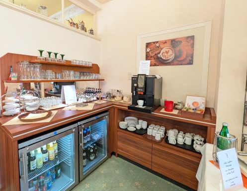 Kaffeebar mit Espressomaschine, Gläsern und Getränken in einem gemütlichen Raum.