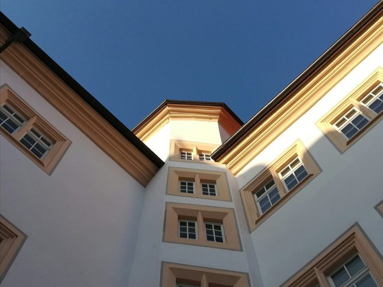 Blick nach oben auf die Fassade eines Gebäudes mit klarer geometrischer Struktur.